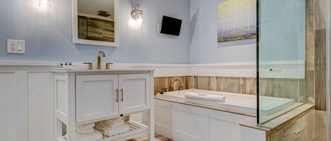 A modern bathroom with a white vanity, a bathtub, and a glass shower enclosure.