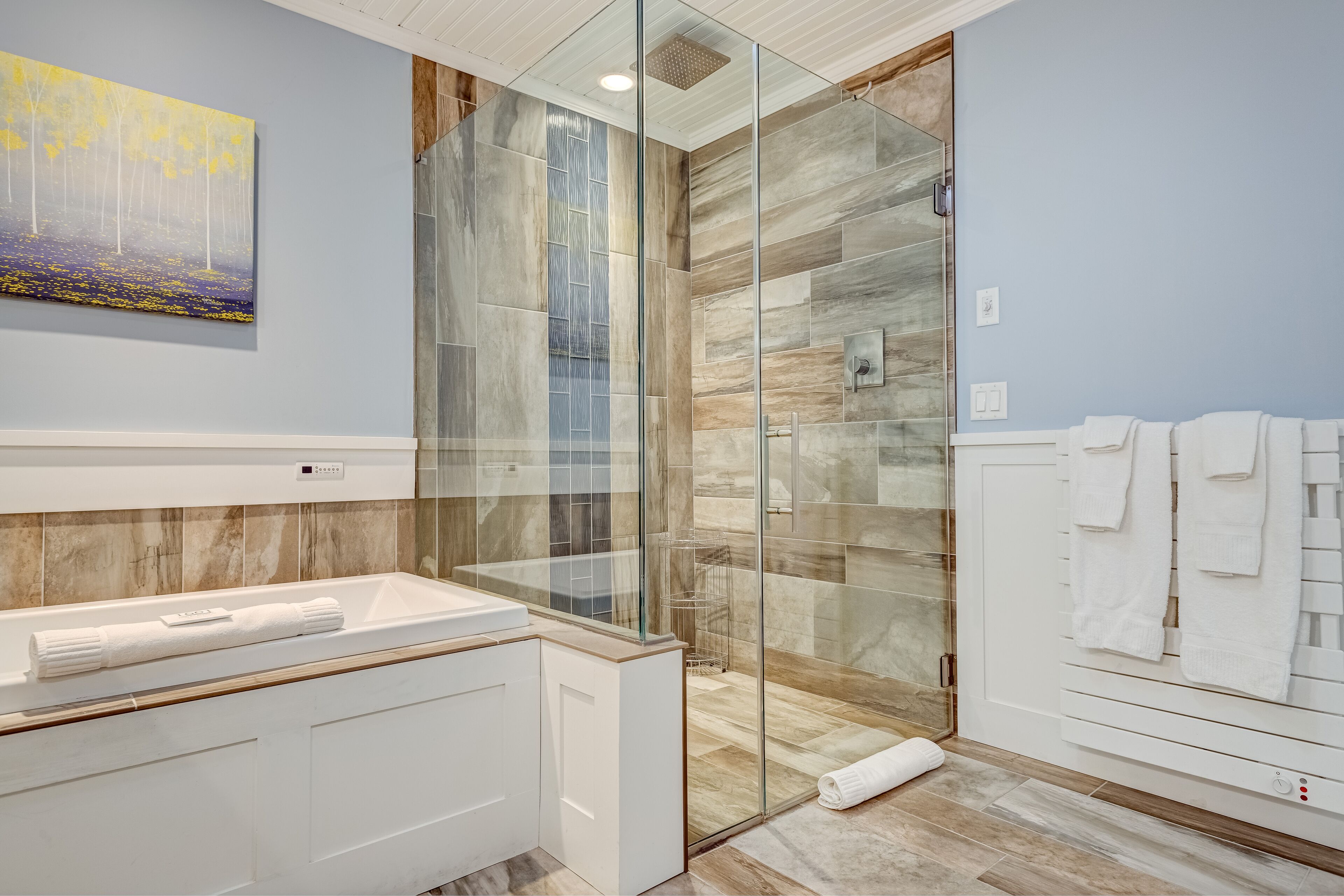 A modern bathroom with a glass-enclosed shower, a white sink, and a towel rack.
