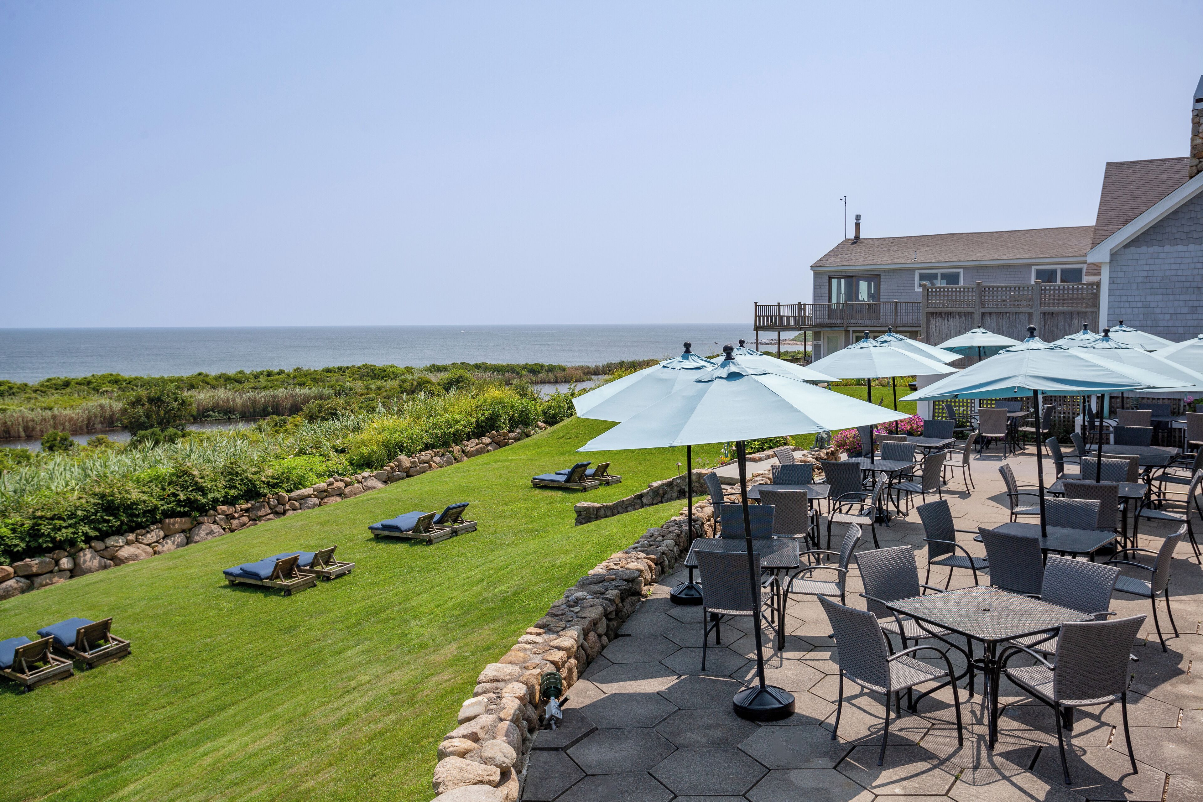 A patio area with outdoor seating and a view of the ocean.