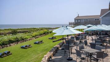 A patio area with outdoor seating and a view of the ocean.