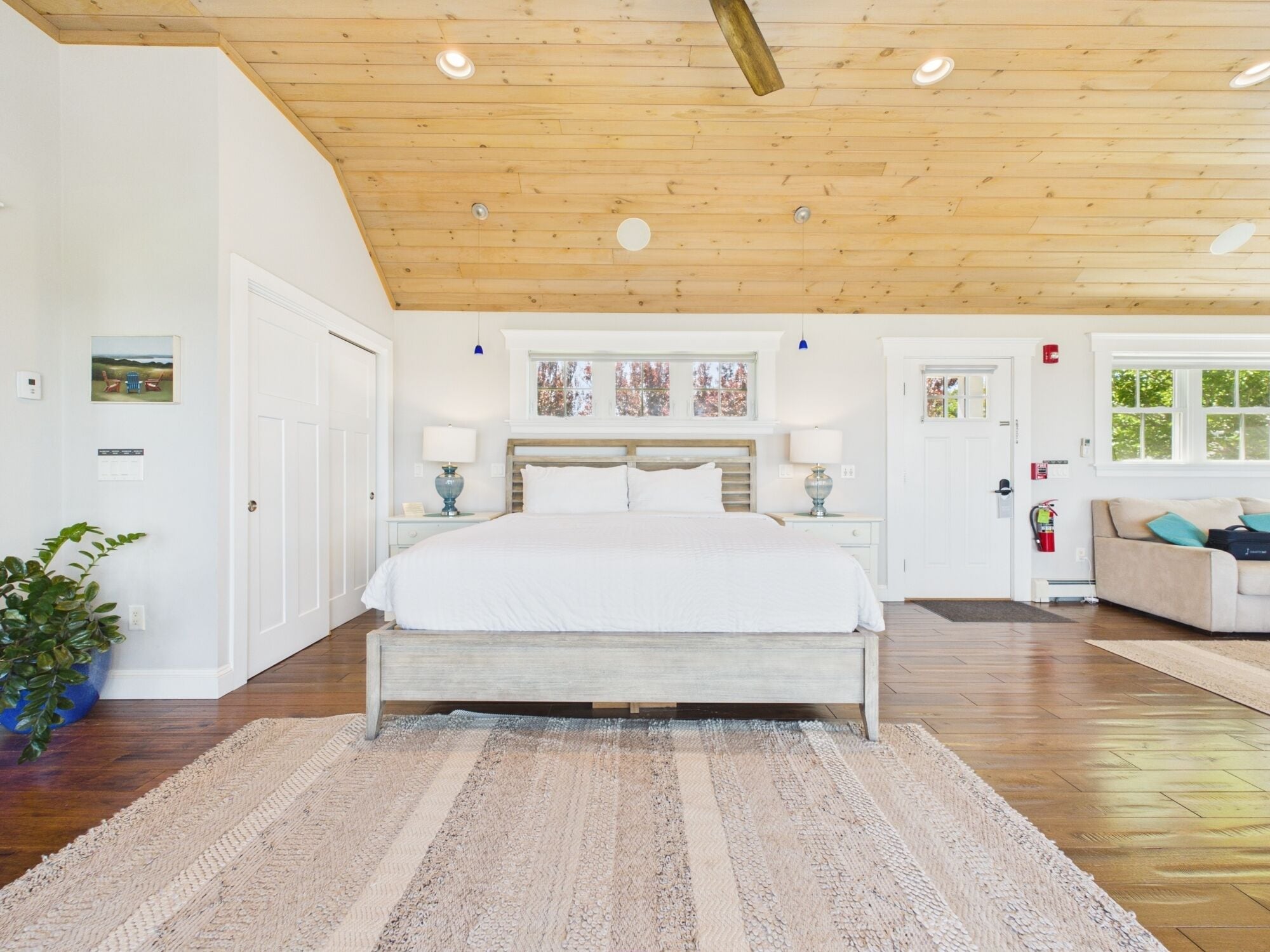A bedroom with a large bed, wooden ceiling, and a view of the outdoors.