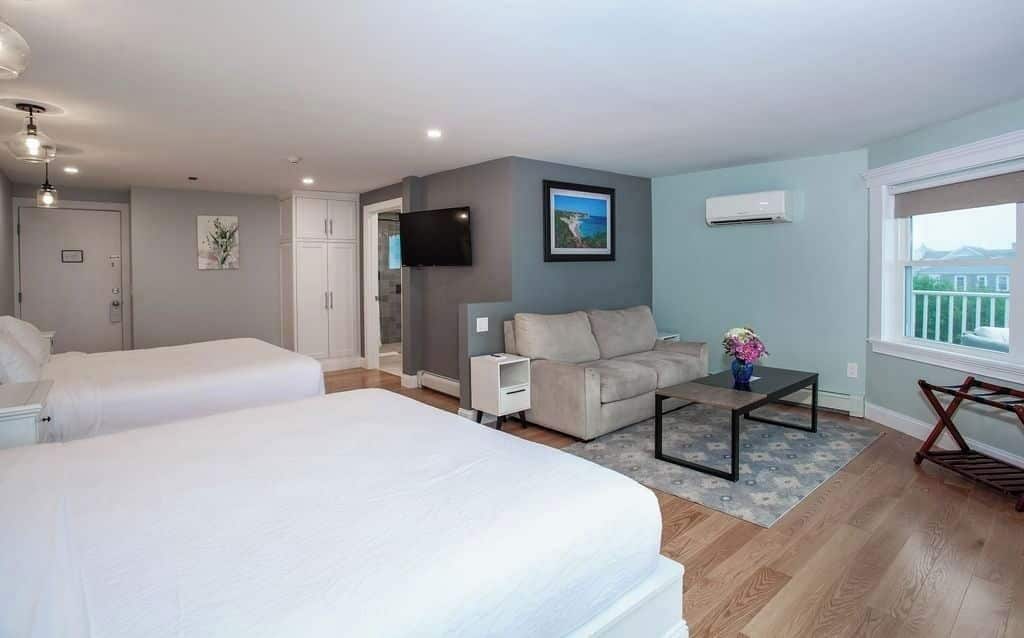 Habitació d'hotel amb dos llits, un sofà, una televisió i una finestra amb vistes.