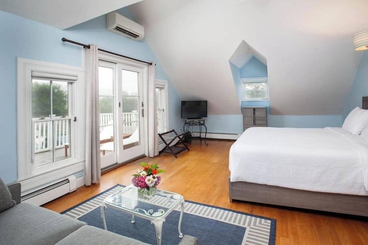 A bedroom with a bed, a TV, a desk, and a balcony.