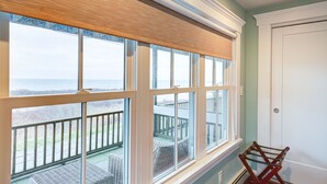 A room with large windows, a view of a balcony with outdoor furniture, and a white door. - The 1661 Inn (Block Island)