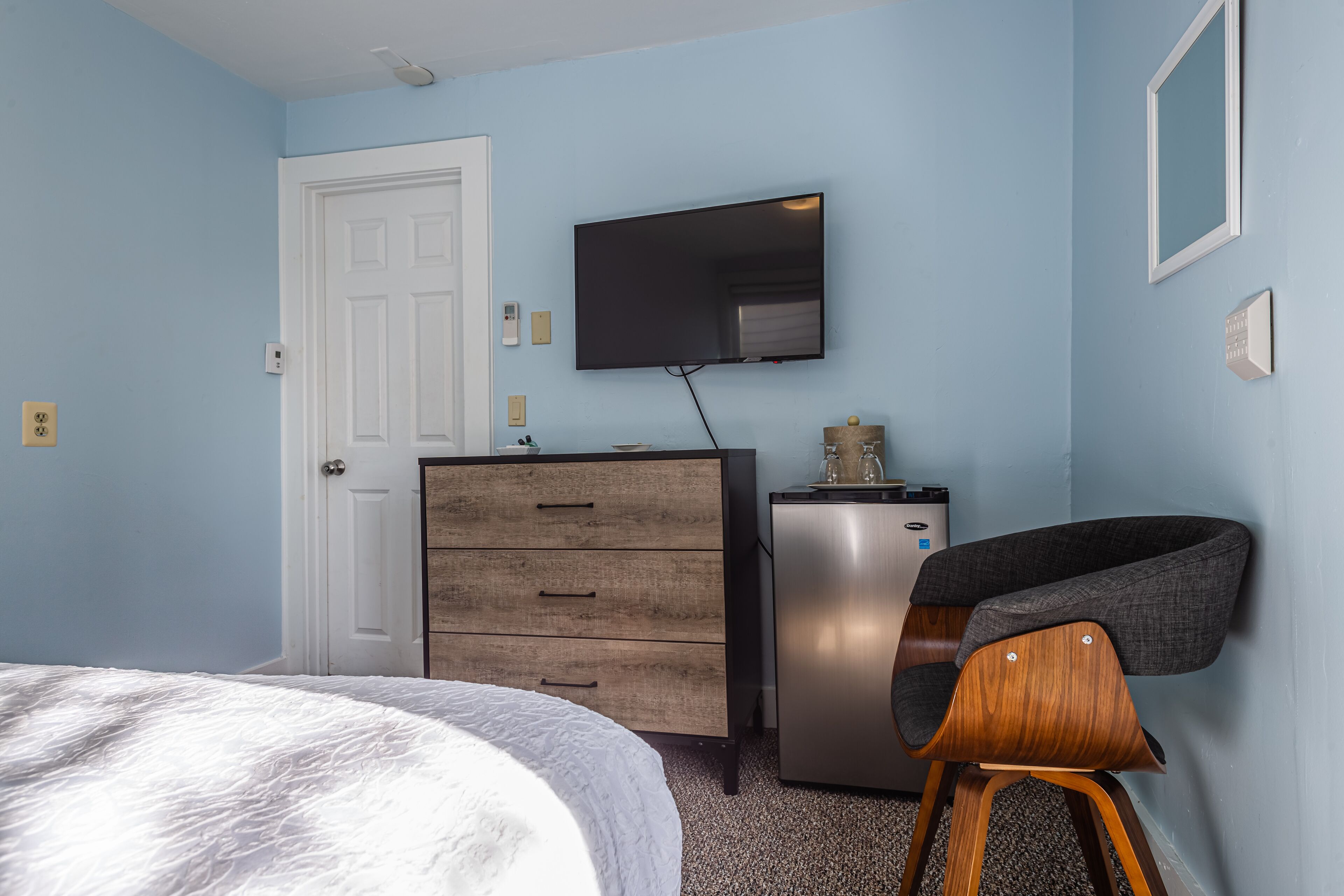 Un dormitorio con cama, cómoda, televisor y silla.