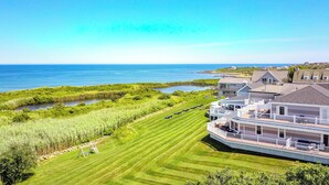 A coastal property with a well-maintained lawn, a swing set, and a view of the ocean. - The 1661 Inn (Block Island)