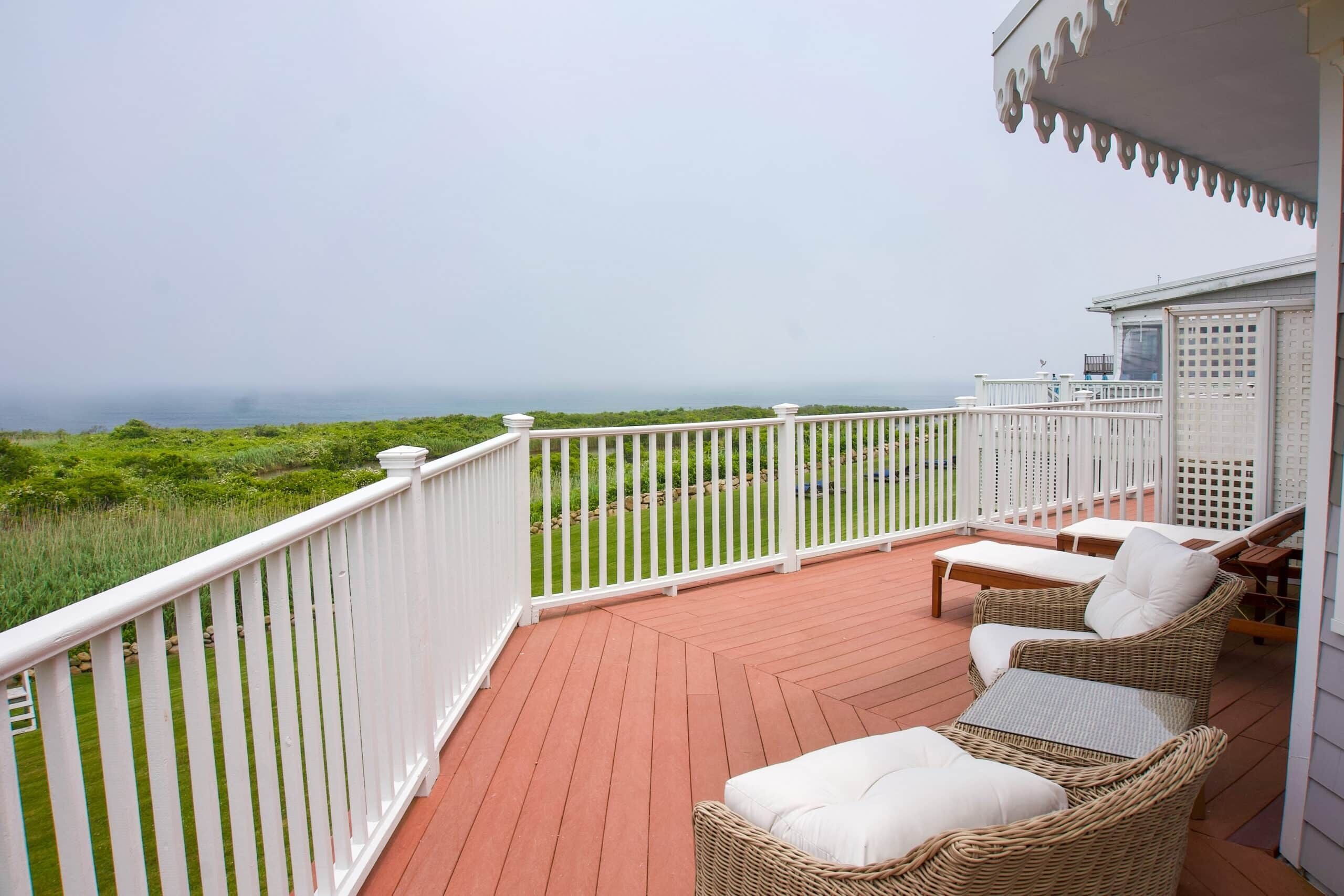 A covered outdoor area with wicker furniture and a white railing.