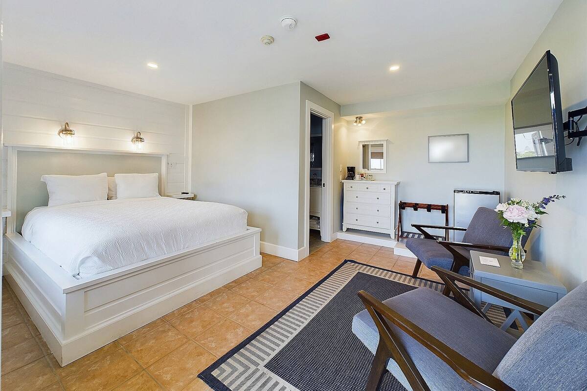 A bedroom with a bed, a dresser, a chair, a desk, and a mirror.