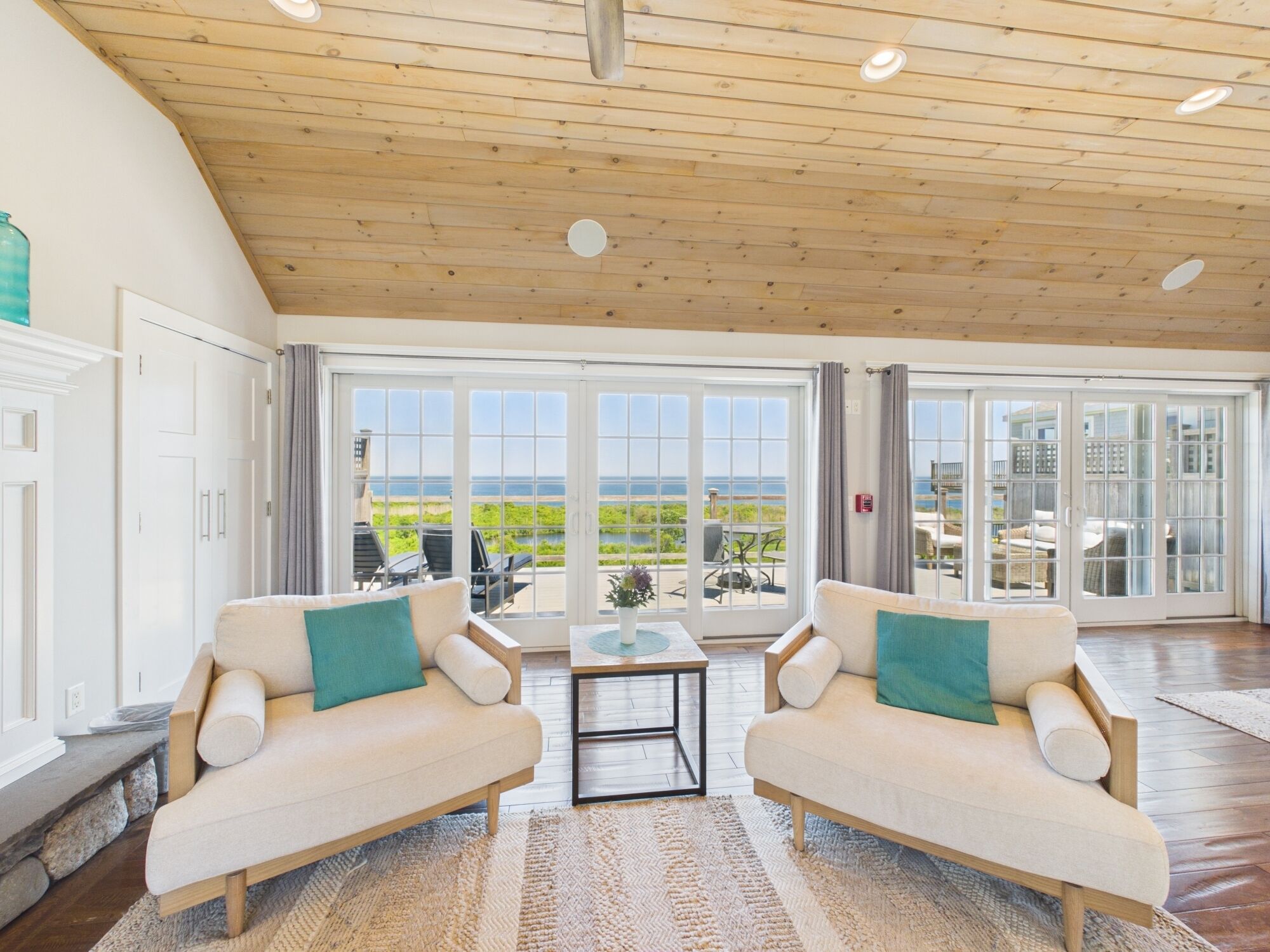 A spacious living area with two sofas, a coffee table, and large sliding glass doors leading to an outdoor patio with a view of the ocean.