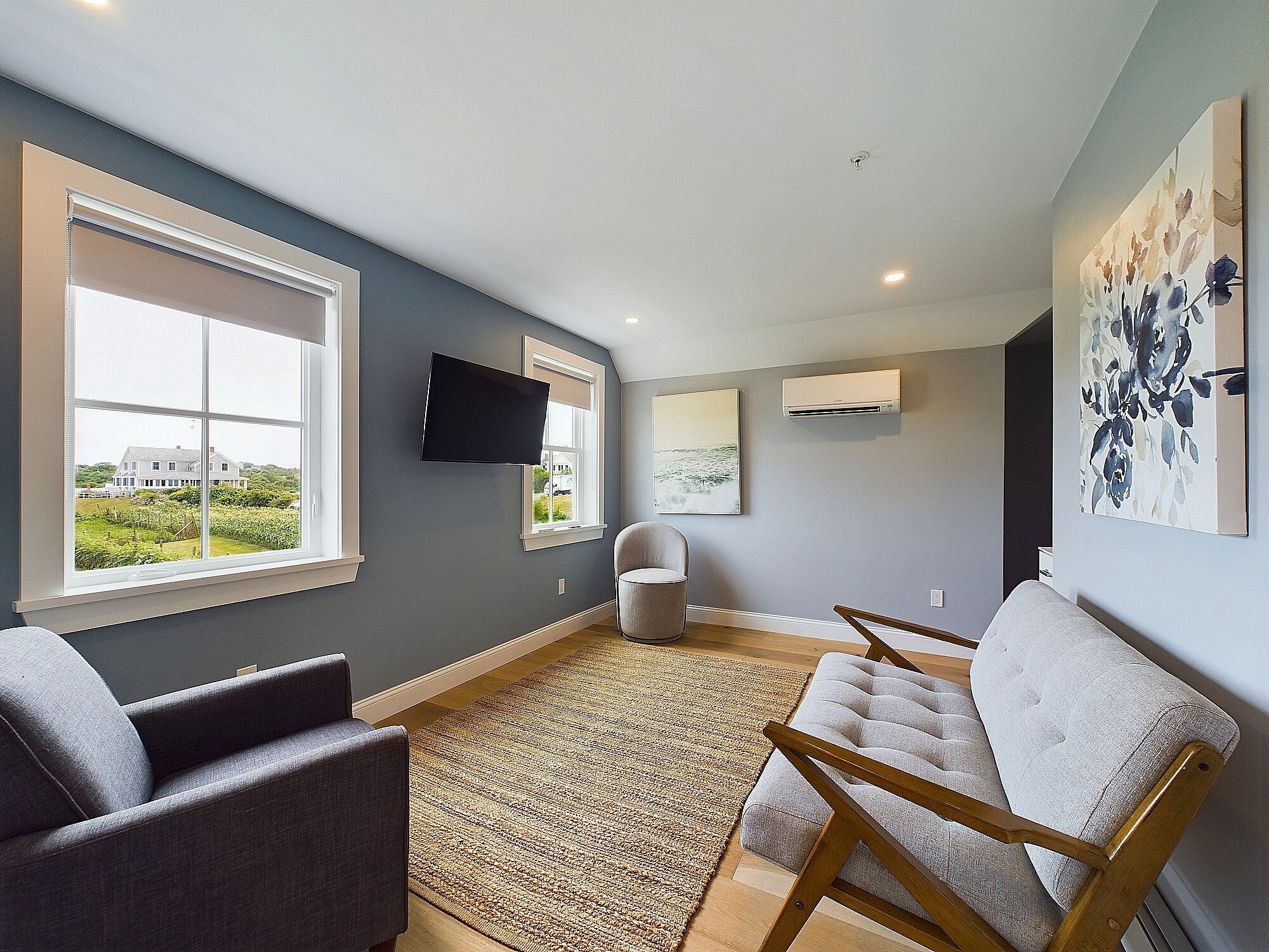 Een moderne woonkamer met een groot raam, een flatscreen televisie en een comfortabele zithoek.