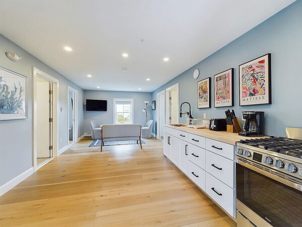 A modern kitchen with a built-in oven, a dining area with a sofa, and artwork on the walls.