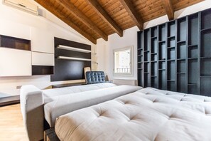 A modern bedroom with a large bed, built-in shelving, and a window.