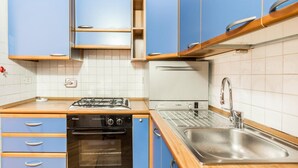 Eine Küche mit blauen Schränken, einem Bosch-Backofen, einem Bosch-Toaster, einer Spüle und einem Herd.