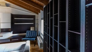 Ein modernes Interieur mit einer Couch, einem blauen Sessel, einem Heizkörper und einer Wand mit Rastermuster.