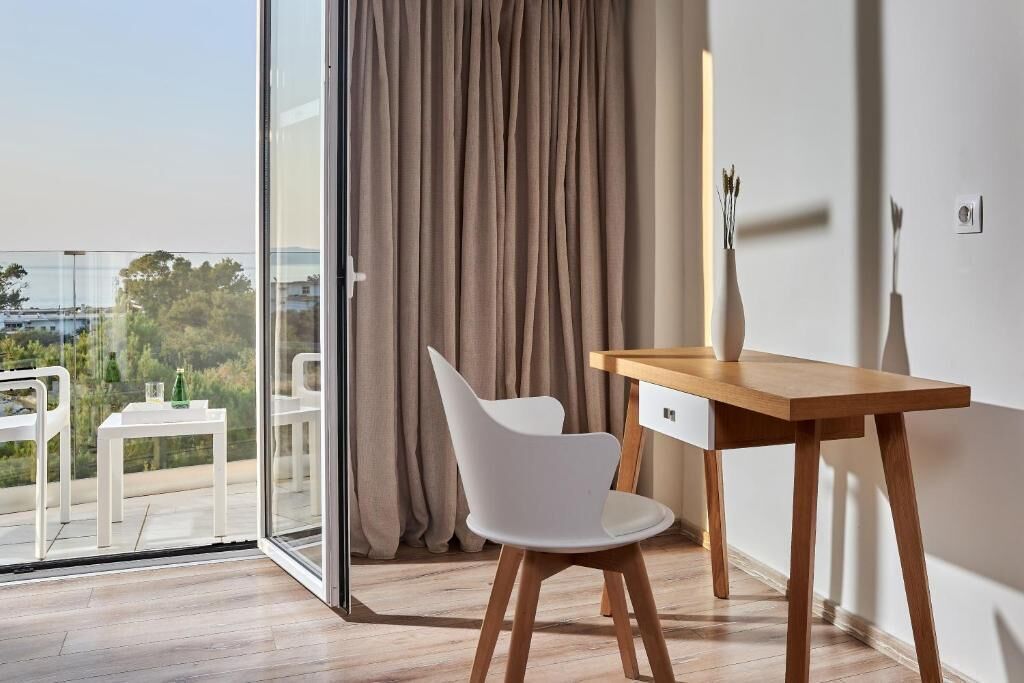 A modern room with a wooden desk, white chair, and a view through a glass door.
