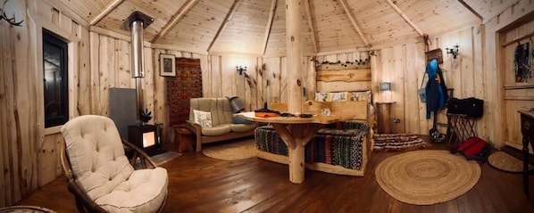 A log cabin interior with a fireplace, a sofa, a dining table, and a bookshelf. - Acorn Glade (York)