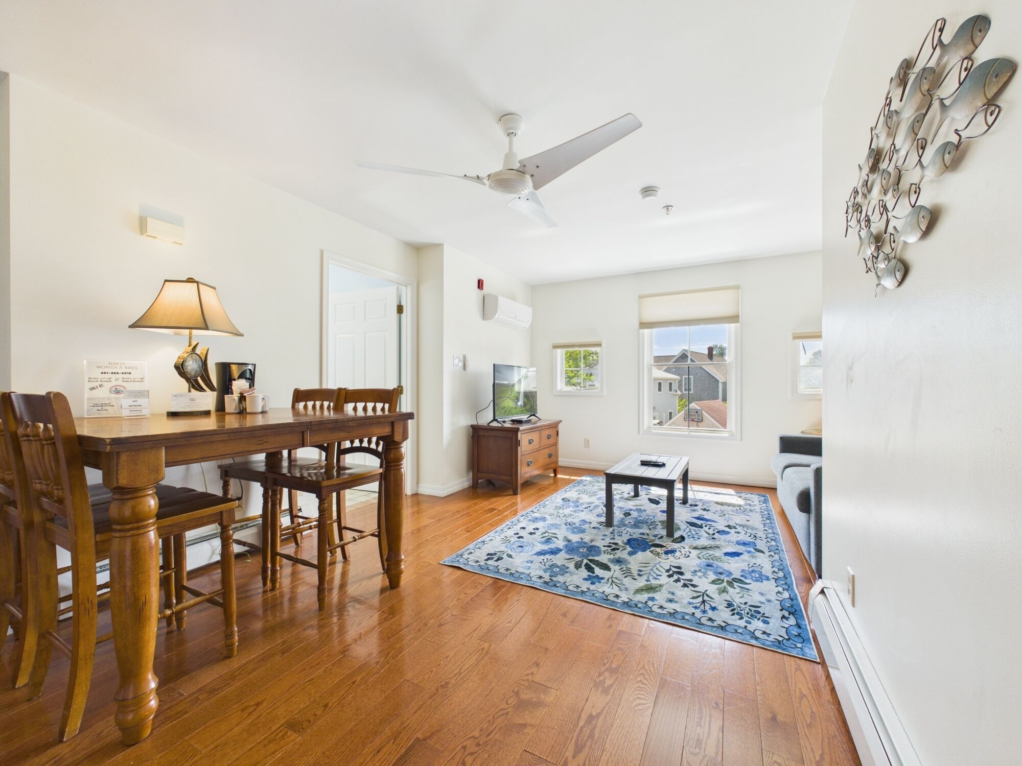 A dining area with a wooden table, chairs, a lamp, and a ceiling fan.