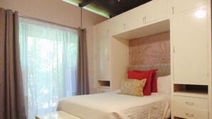 A bedroom with a bed, bedside tables, and built-in storage cabinets.