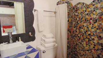 Un baño con lavamanos blanco, inodoro y cortina de ducha con diseño de mosaico.