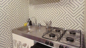 A kitchen with a gas stove, a sink, and a patterned backsplash.