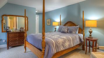 A bedroom with a four-poster bed, a dresser, a chair, and two lamps.
