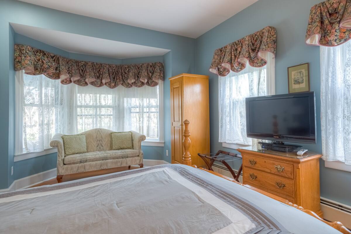 Un dormitorio con una cama grande, un aparador de madera, una televisión, un sofá y un armario.