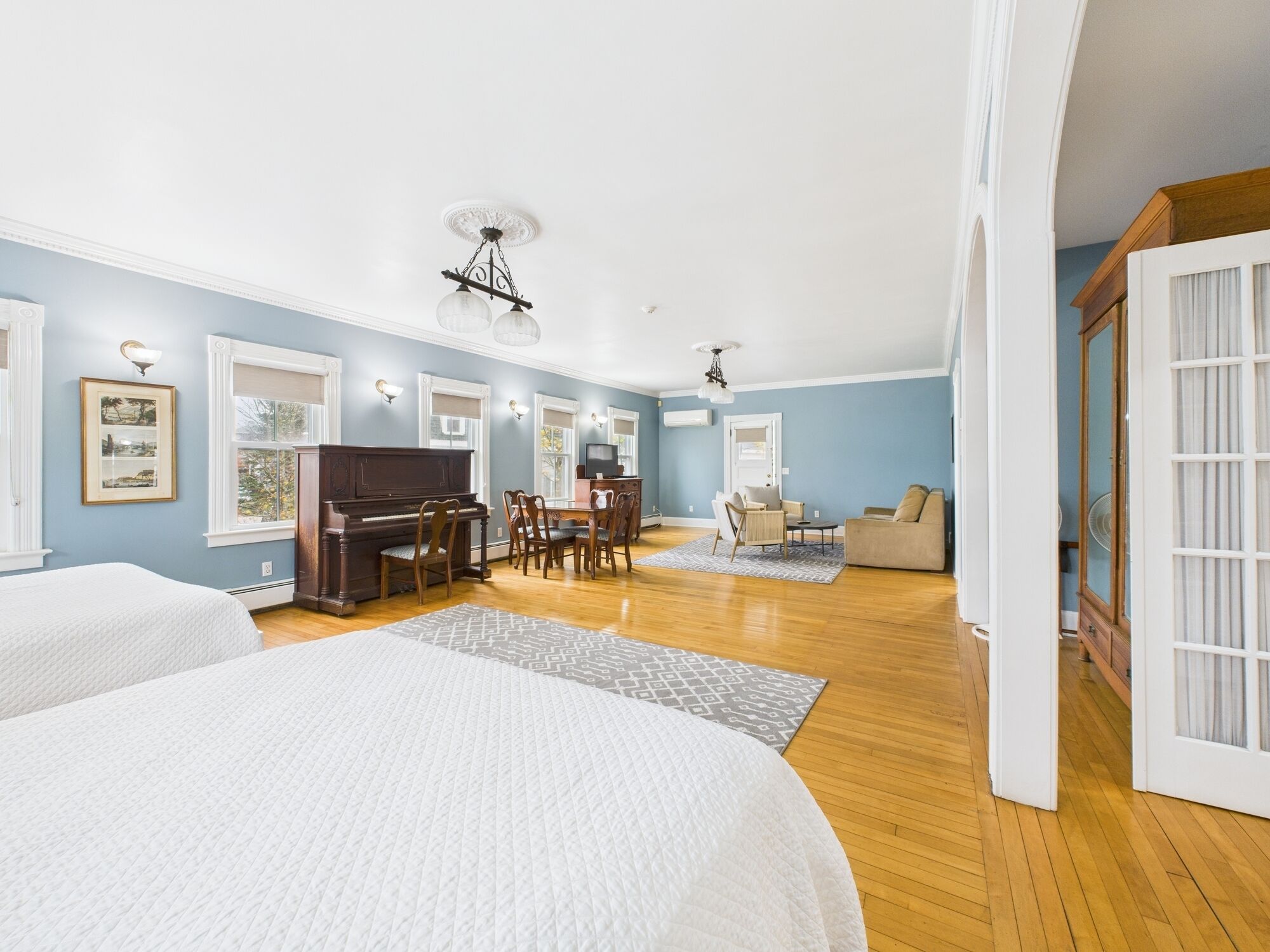 A spacious room with a piano, dining table, and a sofa.