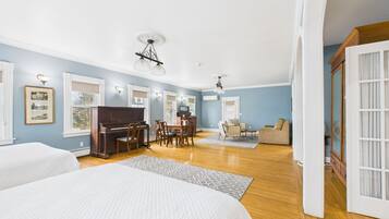 A spacious room with a piano, dining table, and a sofa.