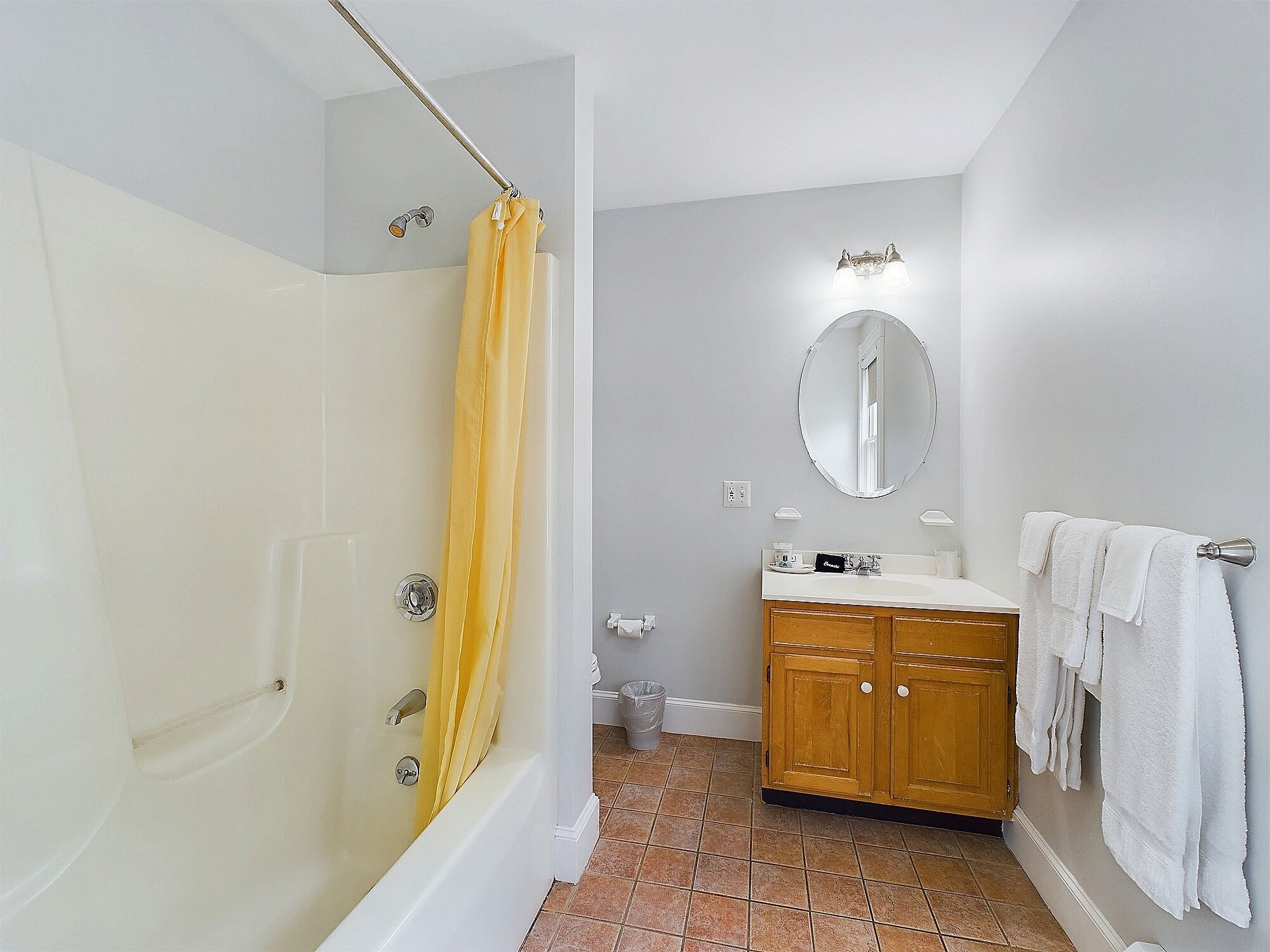 Un baño con bañera, cortina de ducha, lavabo con espejo y toallero.