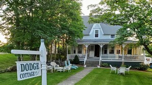 A cottage with a porch, outdoor seating, and a sign indicating 'Dodge Cottage.' - Dodge Cottage (Block Island)