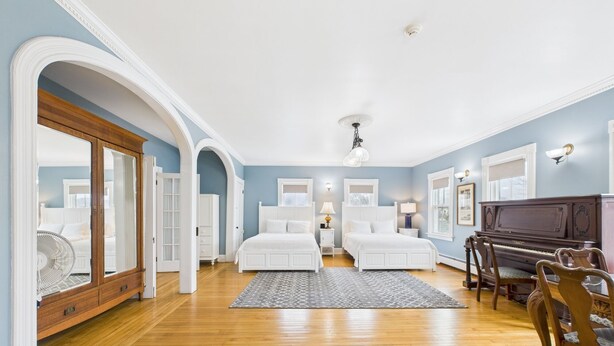 A bedroom with two beds, a piano, and a fan. - Dodge Cottage (Block Island)
