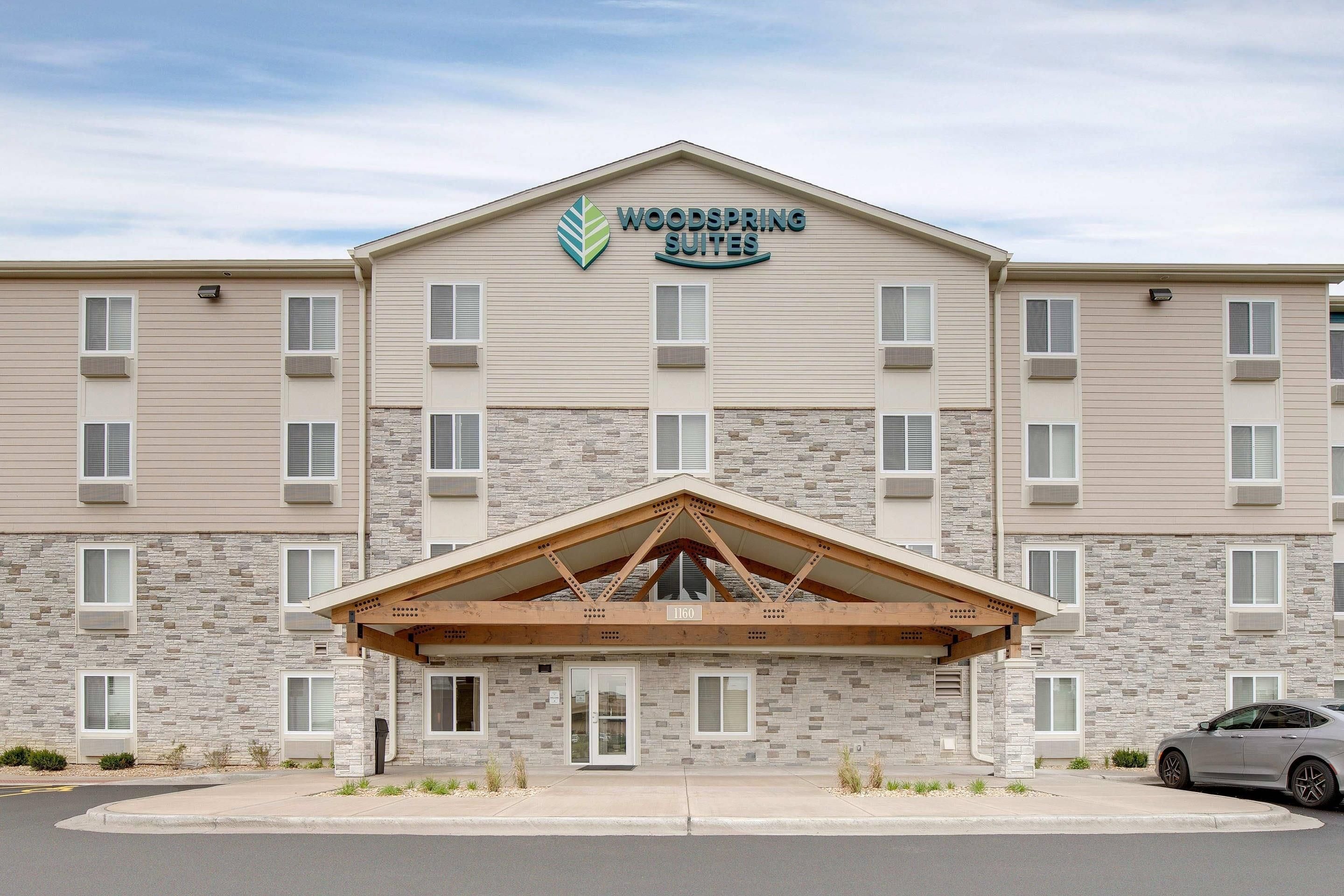A hotel with a stone facade, a covered entrance, and a sign indicating it offers suites.