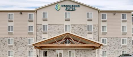 A hotel with a stone facade, a covered entrance, and a sign indicating it offers suites.