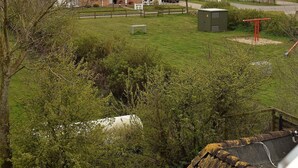 A grassy outdoor area with a playground, a small shed, and a red structure. - Haus Uthlande (Dagebuell)