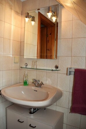 A bathroom with a beige sink, a mirror, and a wooden door. - Haus Wattblick (Dagebuell)
