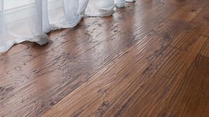 Un suelo de madera con cortinas blancas y traslúcidas.