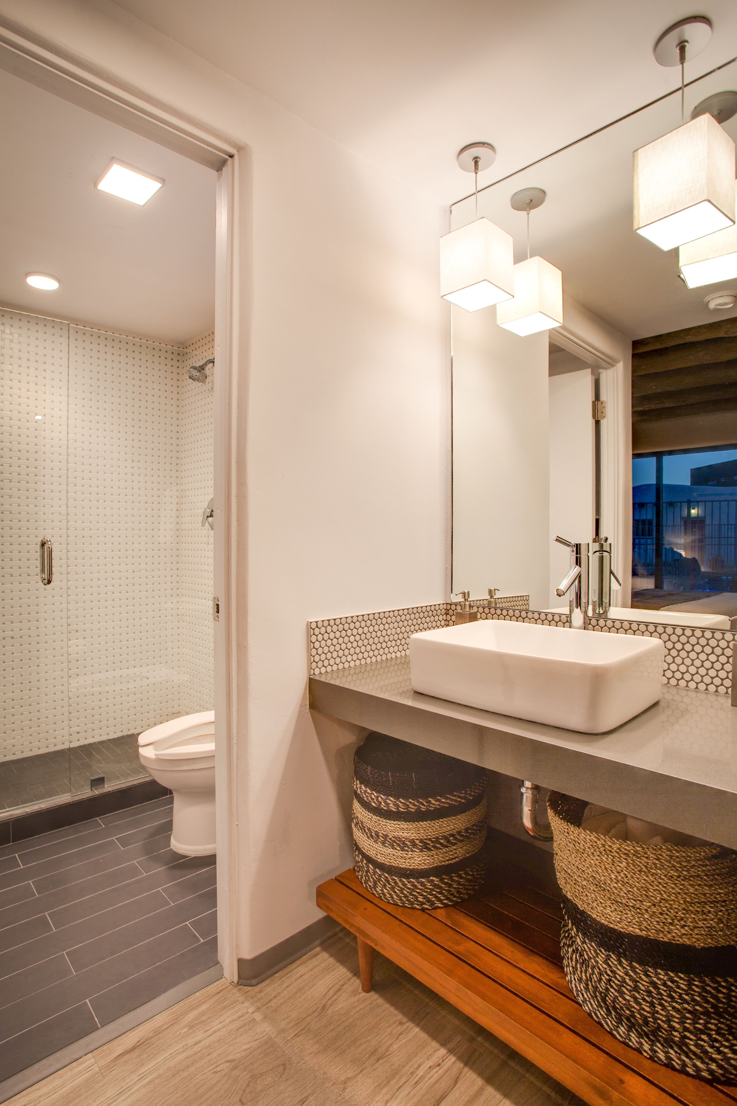 A modern bathroom with a large mirror, a rectangular sink, and a shower area.