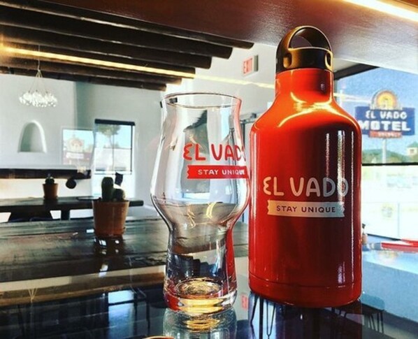 A glass and a red water bottle with the text "EL VADO STAY UNIQUE" on a counter.