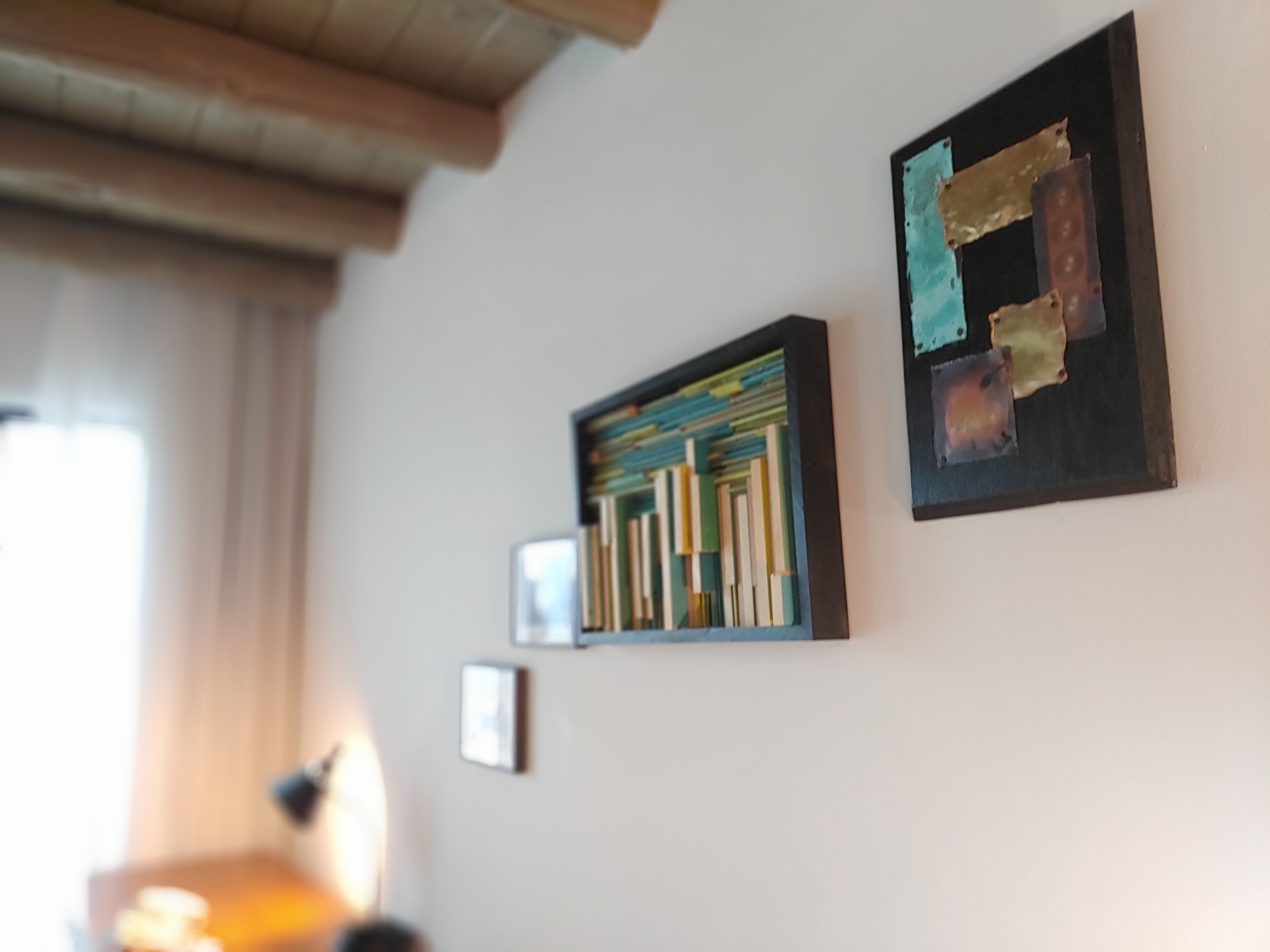 Una stanza con una libreria, un quadro astratto incorniciato e una piccola foto appesa al muro.