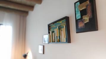 Una stanza con una libreria, un quadro astratto incorniciato e una piccola foto appesa al muro.