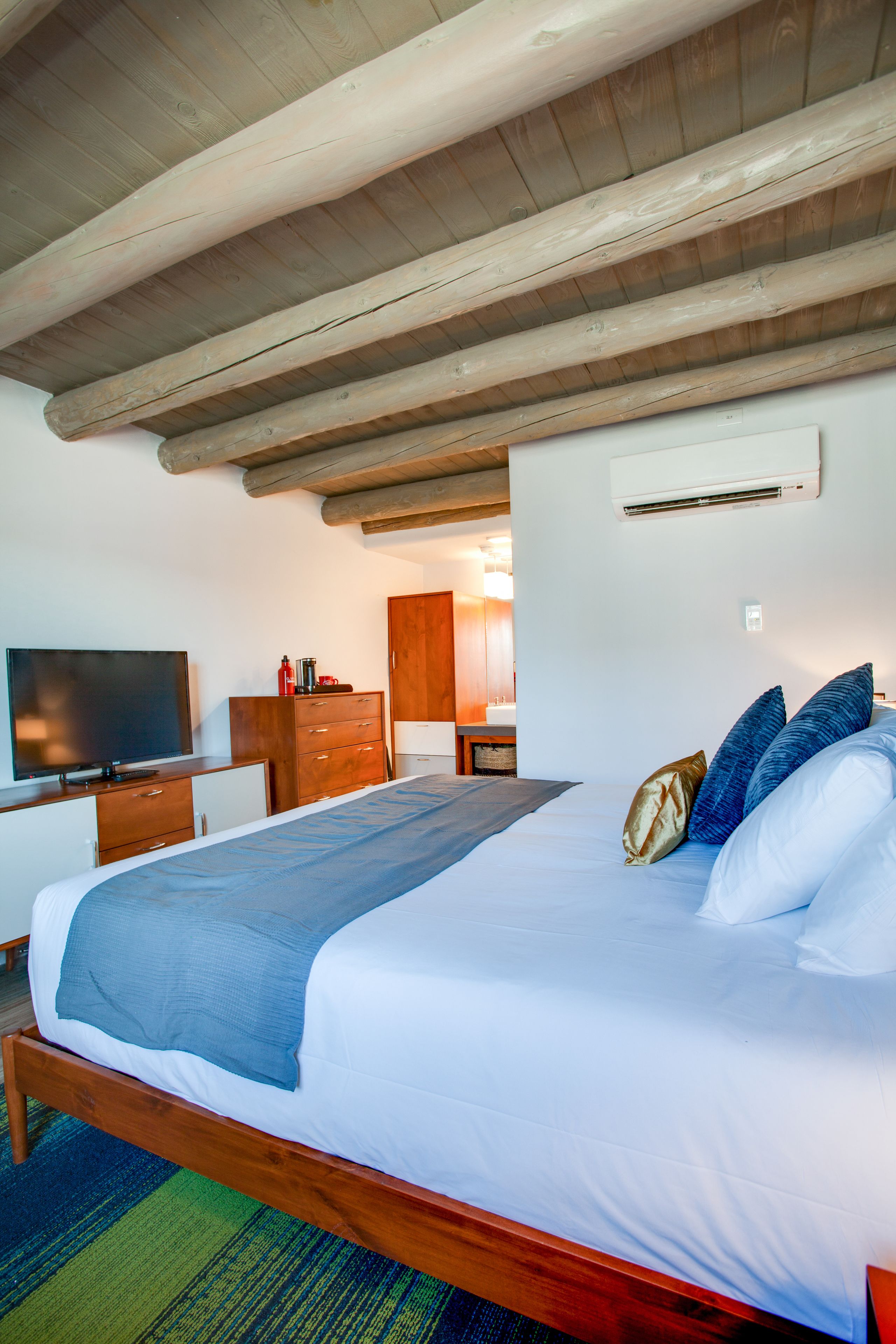 A bedroom with a wooden bed, a television, a wardrobe, and an air conditioning unit.