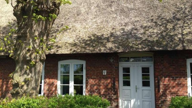 A traditional brick building with a thatched roof, white-framed windows, and a central door. - Haus Frieda (Risum-Lindholm)