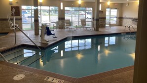 Una piscina interior con señal de profundidad de 94 centímetros, sillas de descanso y vistas al exterior.