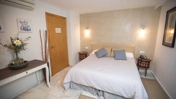A bedroom with a bed, bedside tables, a desk, and a wall-mounted air conditioner.