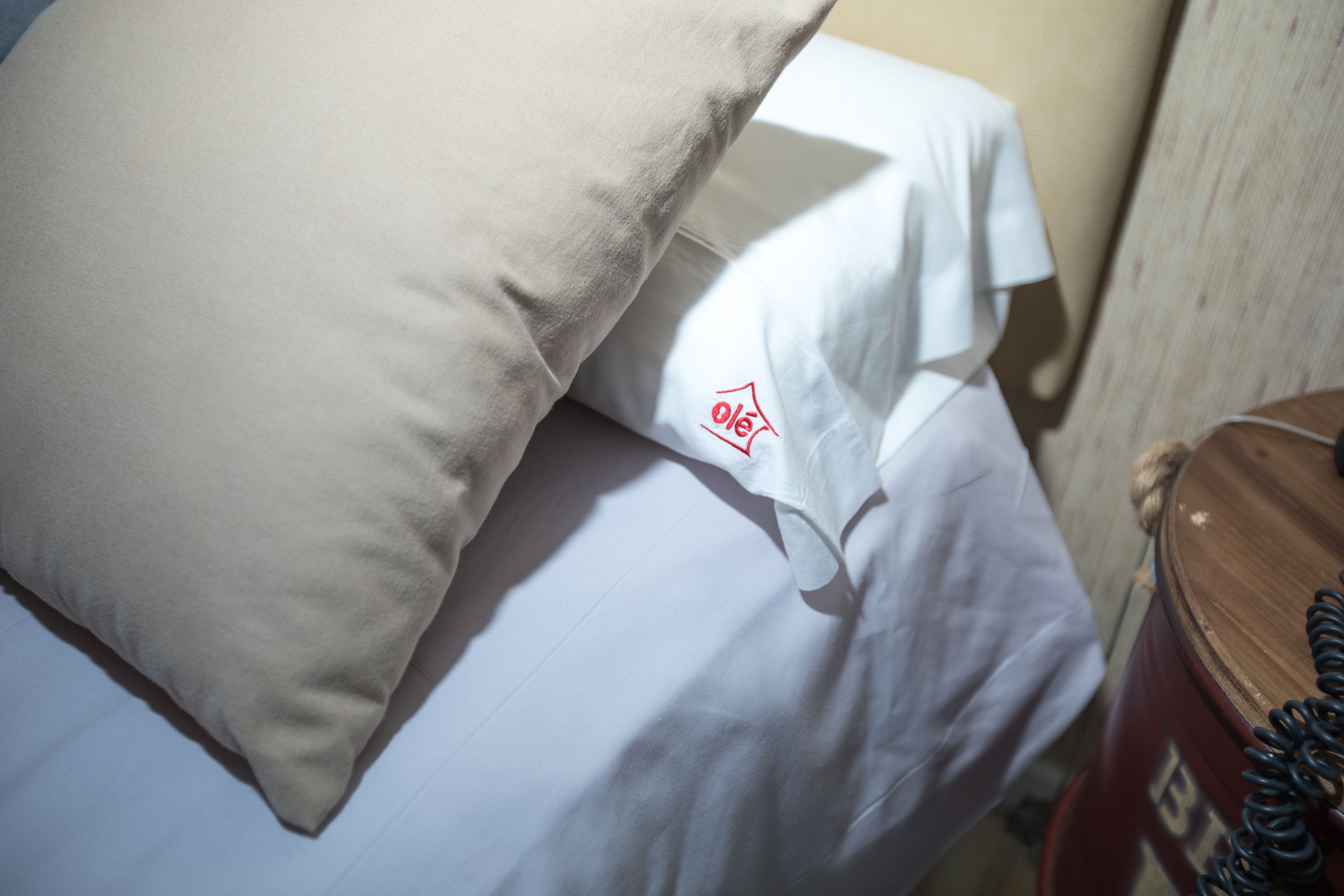 Una cama con ropa blanca y una almohada con un logotipo.