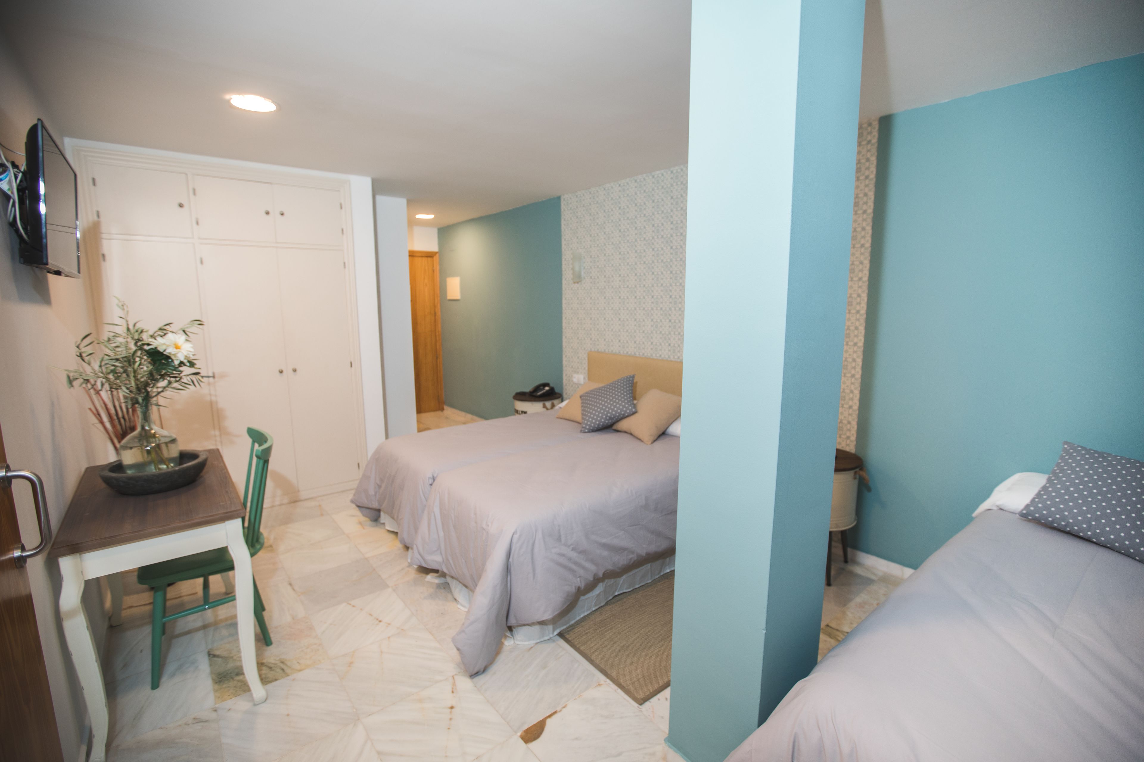 A bedroom with two beds, a desk, and a chair.