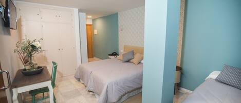 A bedroom with two beds, a desk, and a chair.