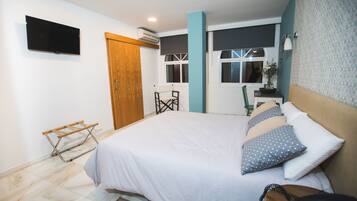 Un dormitorio con una cama grande, un televisor montado en la pared y un ventanal con vistas al exterior.