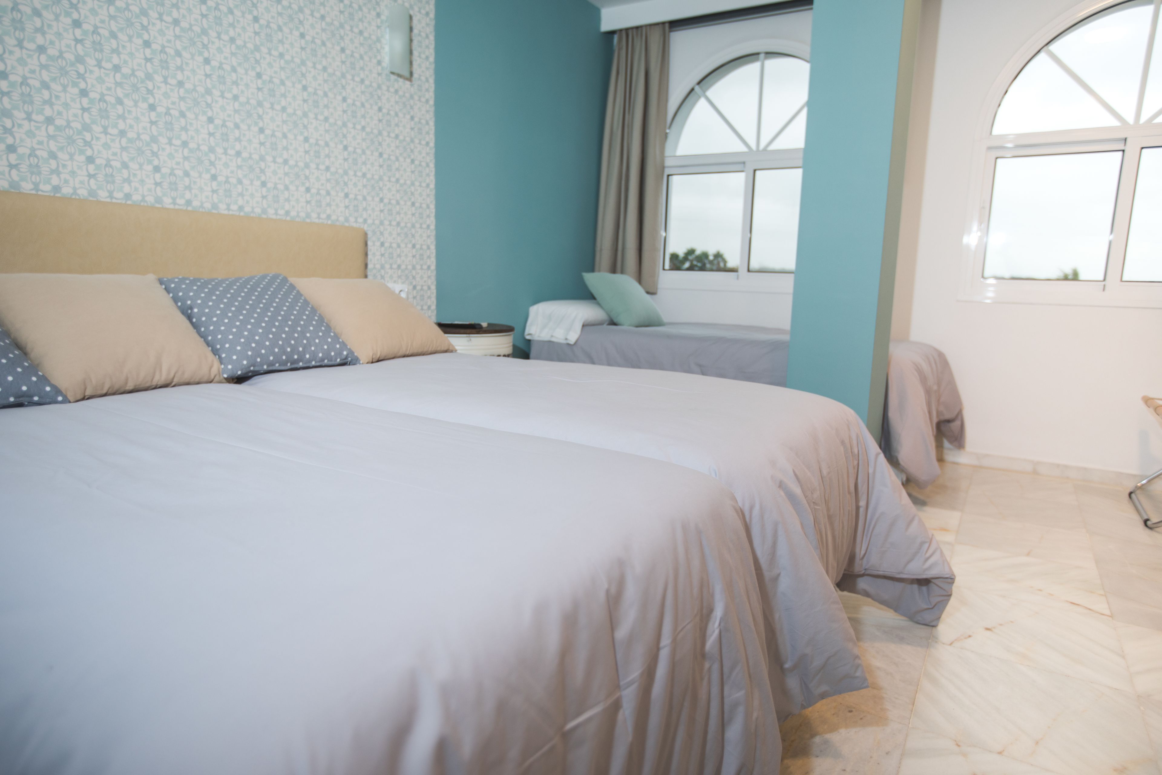 A bedroom with two beds, a window, and a nightstand.