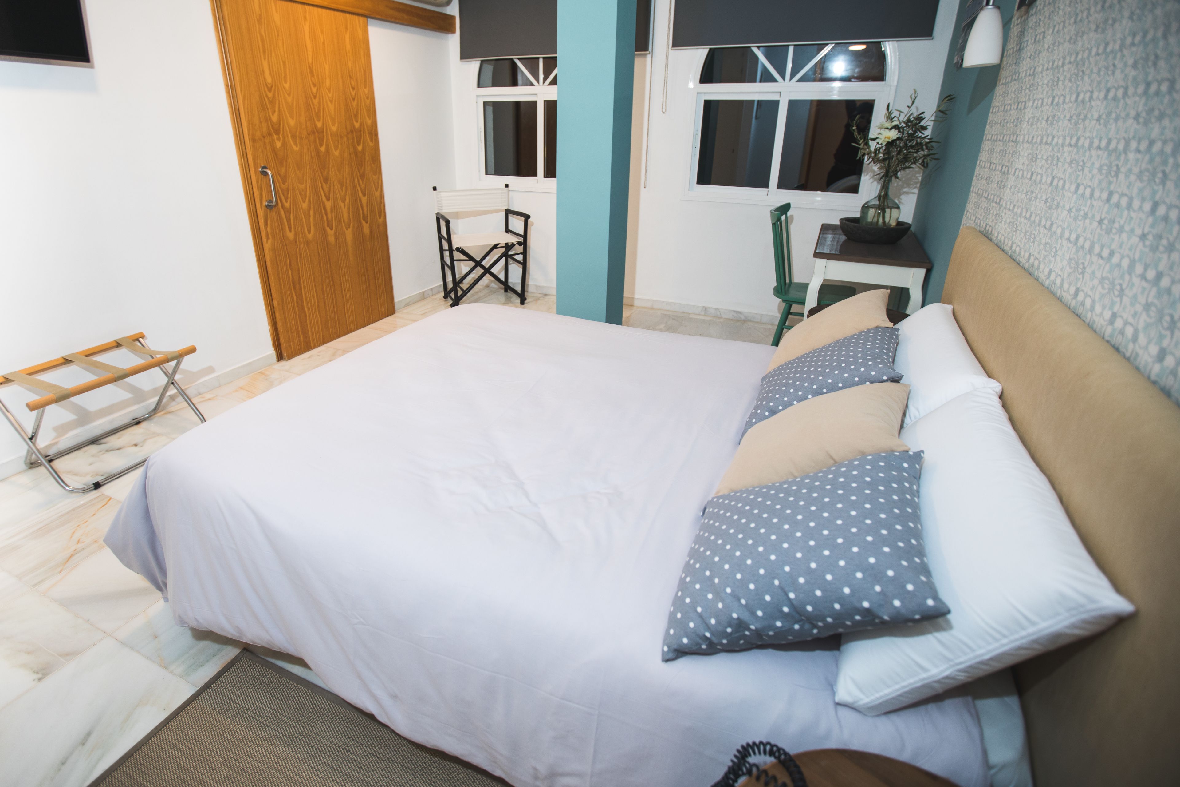 Une chambre avec un grand lit, une armoire en bois, une petite table avec une chaise et une fenêtre donnant sur un beau paysage.